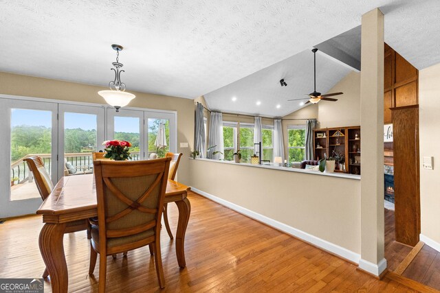 dining space featuring ceiling fan, vaulted ceiling, light hardwood / wood-style flooring, and a textured ceiling