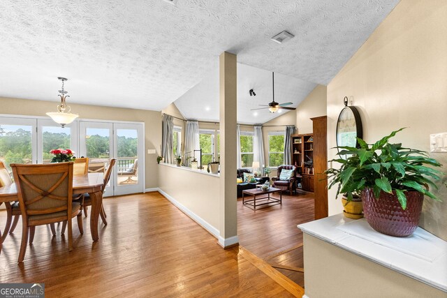 dining area with wood-type flooring, lofted ceiling, ceiling fan, and a textured ceiling