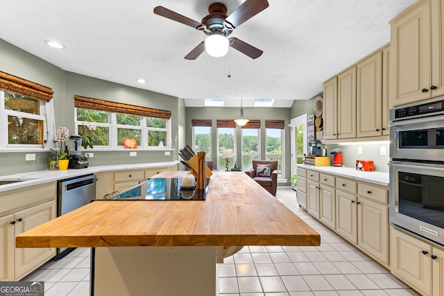 kitchen with butcher block countertops, stainless steel appliances, a healthy amount of sunlight, and a kitchen island