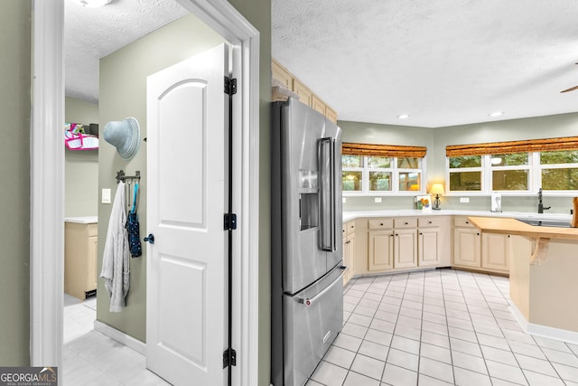 kitchen featuring light tile patterned floors, high end refrigerator, a textured ceiling, and light brown cabinets