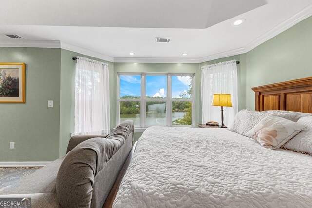 bedroom with french doors, connected bathroom, light hardwood / wood-style flooring, ornamental molding, and a tray ceiling