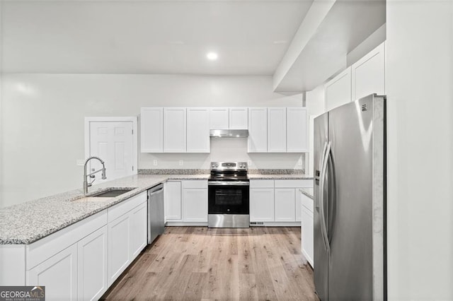 kitchen with sink, white cabinetry, appliances with stainless steel finishes, light stone countertops, and light hardwood / wood-style floors