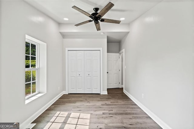 unfurnished bedroom featuring hardwood / wood-style floors, ceiling fan, and a closet