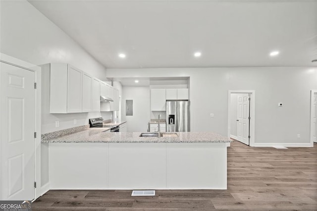 kitchen featuring sink, appliances with stainless steel finishes, kitchen peninsula, hardwood / wood-style flooring, and white cabinets