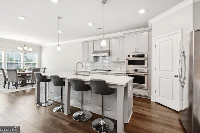 kitchen with stainless steel appliances, sink, a kitchen island with sink, and decorative light fixtures