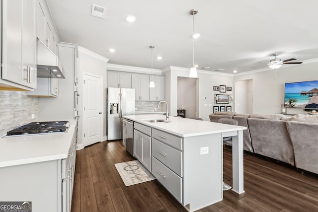 kitchen featuring appliances with stainless steel finishes, sink, dark hardwood / wood-style flooring, hanging light fixtures, and a kitchen island with sink