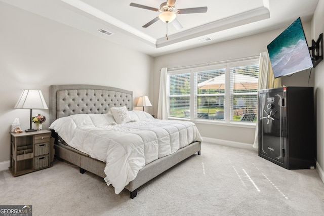 bedroom with ceiling fan, a raised ceiling, and light carpet