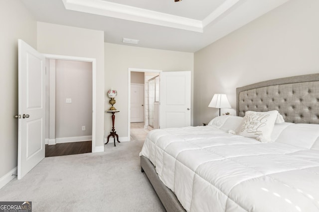 bedroom with light carpet and a tray ceiling