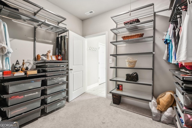 walk in closet with light carpet