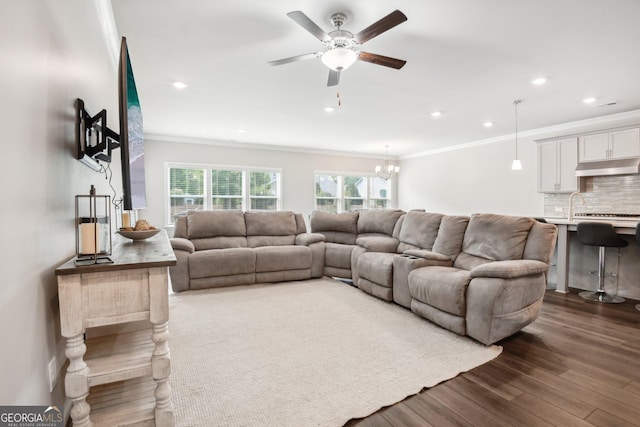 living room featuring ornamental molding, dark hardwood / wood-style floors, and ceiling fan with notable chandelier