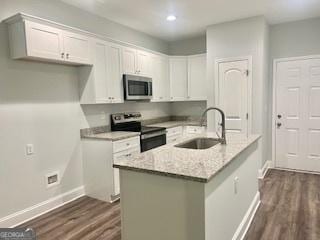 kitchen featuring sink, dark wood-type flooring, white cabinetry, stainless steel appliances, and light stone countertops