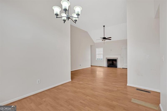 unfurnished living room featuring vaulted ceiling, ceiling fan with notable chandelier, and light wood-type flooring