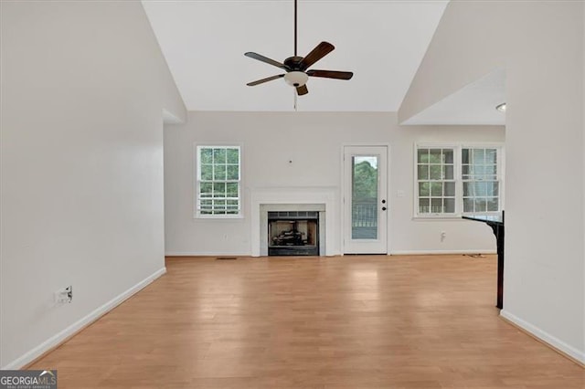 unfurnished living room with ceiling fan, high vaulted ceiling, and light wood-type flooring