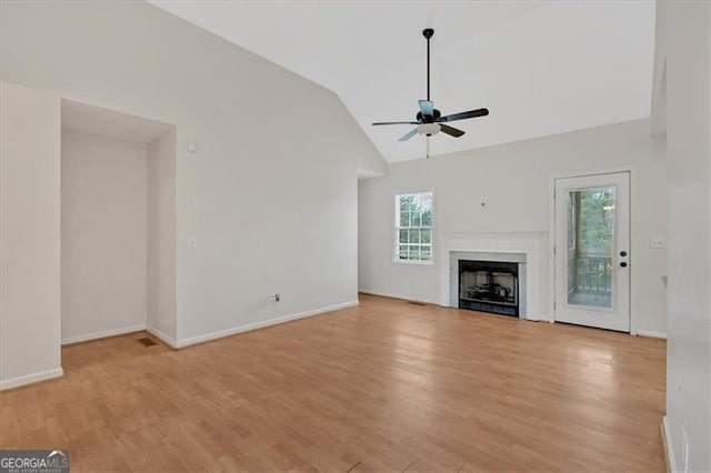 unfurnished living room with baseboards, lofted ceiling, light wood-style flooring, ceiling fan, and a fireplace