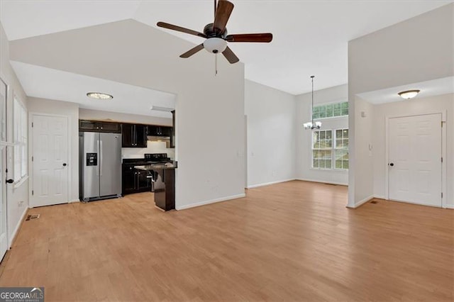 unfurnished living room featuring lofted ceiling, light wood-style flooring, baseboards, and ceiling fan with notable chandelier