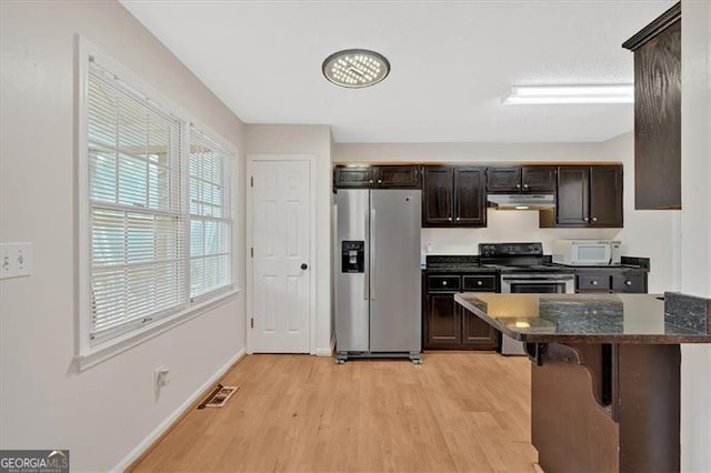 kitchen featuring baseboards, visible vents, light wood-style floors, stainless steel appliances, and under cabinet range hood