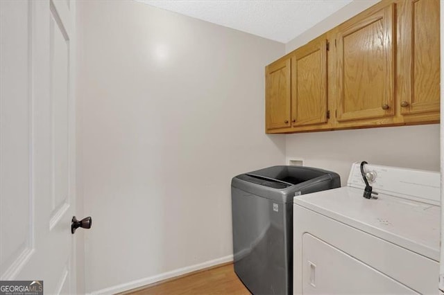 laundry area with cabinets, light wood-type flooring, and independent washer and dryer