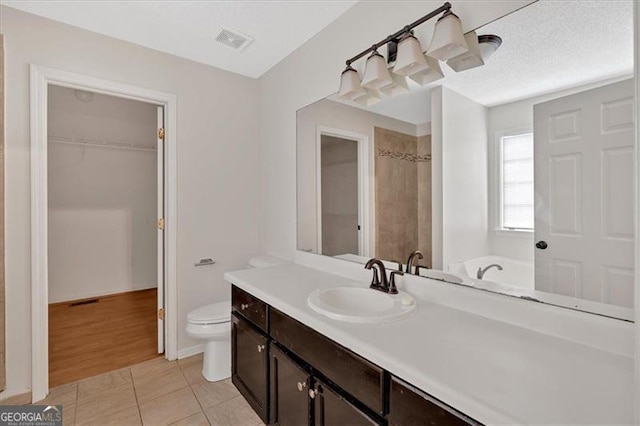 bathroom with tile patterned flooring, vanity, toilet, a bath, and a textured ceiling