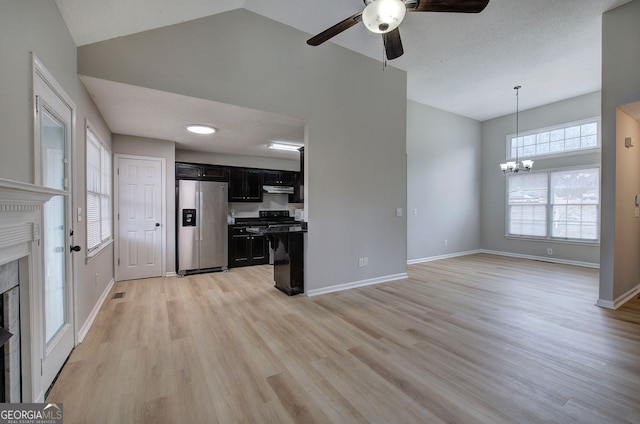 kitchen with dark cabinetry, a premium fireplace, stainless steel fridge, under cabinet range hood, and baseboards