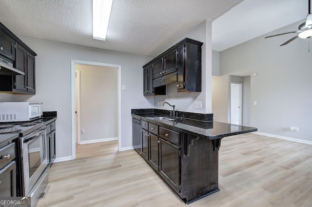 kitchen featuring white microwave, a sink, dishwasher, dark stone countertops, and stainless steel range with electric stovetop