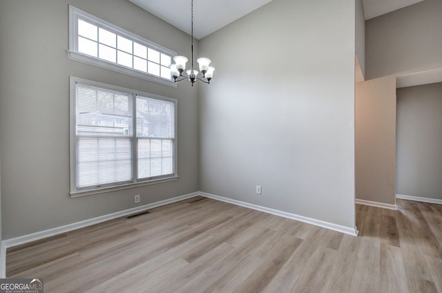 unfurnished room featuring a wealth of natural light, visible vents, a notable chandelier, and wood finished floors