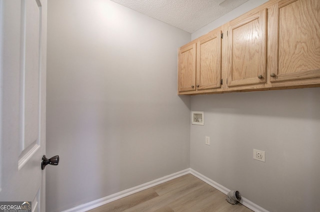 washroom featuring a textured ceiling, hookup for a washing machine, light wood-style floors, baseboards, and cabinet space