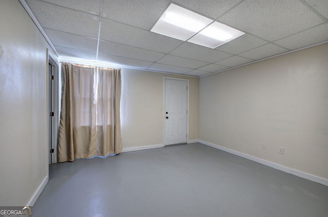 spare room featuring baseboards, a drop ceiling, and finished concrete floors