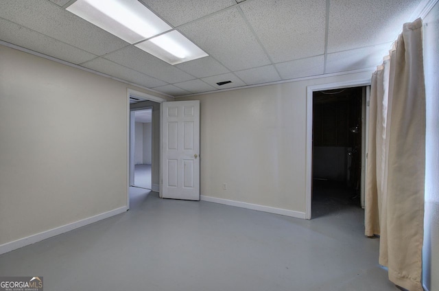 finished below grade area featuring a paneled ceiling, visible vents, and baseboards