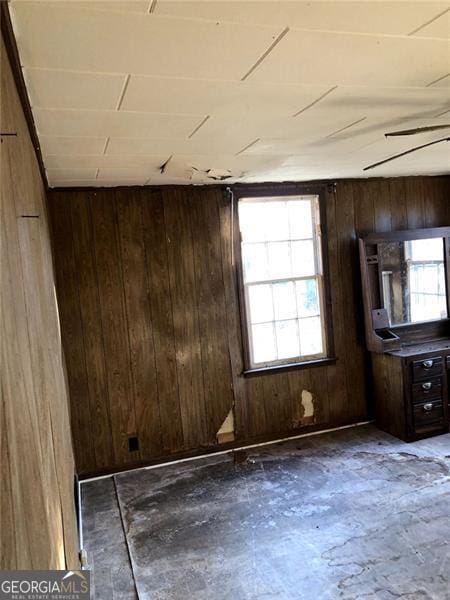 unfurnished room with plenty of natural light and wooden walls