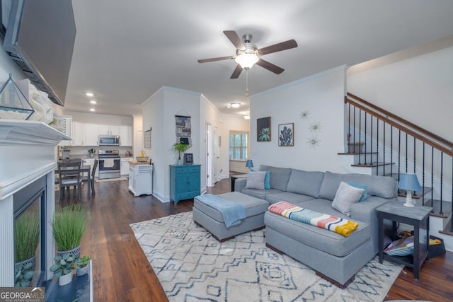 living room featuring dark wood-type flooring, ornamental molding, and ceiling fan