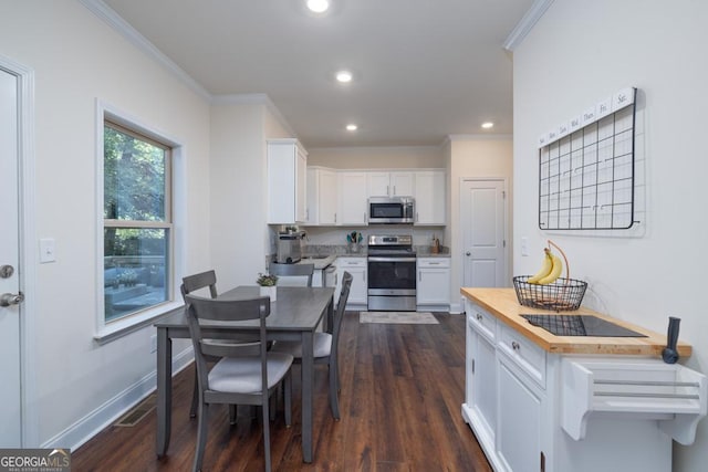 kitchen featuring white cabinetry, appliances with stainless steel finishes, crown molding, and butcher block countertops