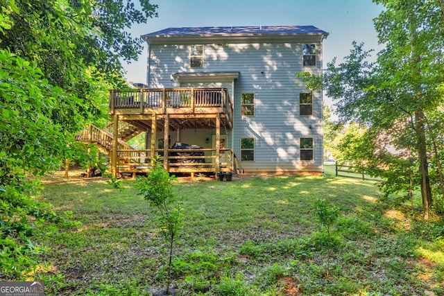 rear view of house featuring a wooden deck and a yard