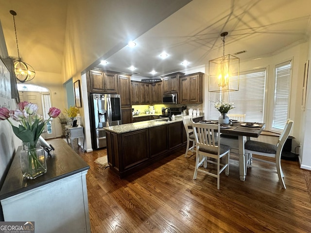 kitchen with pendant lighting, appliances with stainless steel finishes, dark hardwood / wood-style flooring, and a kitchen island