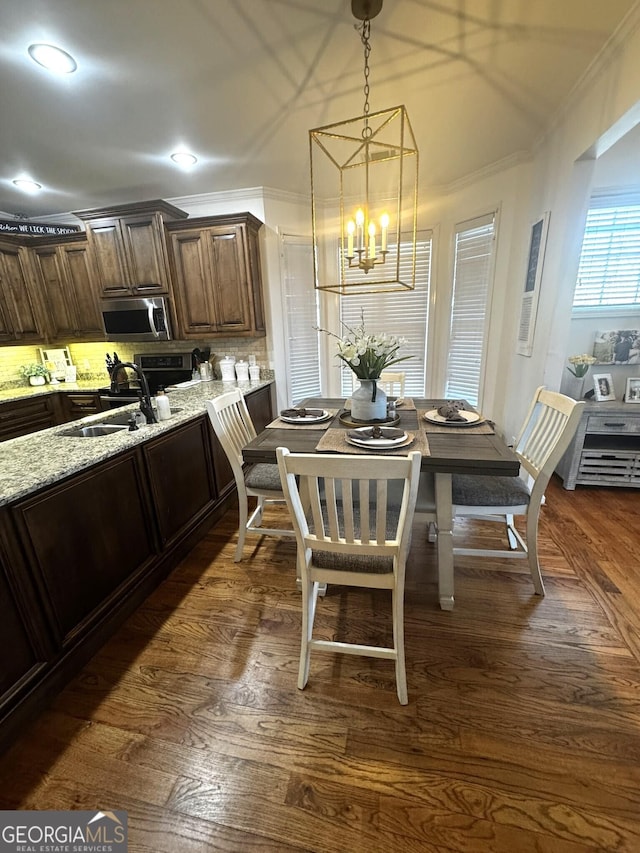 dining area featuring ornamental molding, sink, dark wood-type flooring, and an inviting chandelier