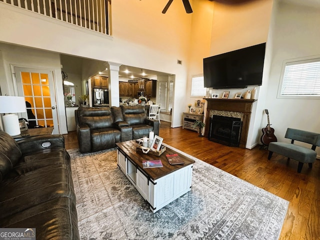 living room with hardwood / wood-style flooring, a high ceiling, ceiling fan, and ornate columns