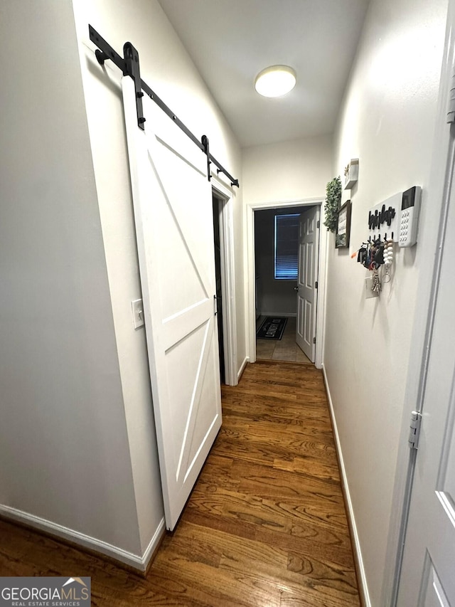 hallway with a barn door and dark hardwood / wood-style floors