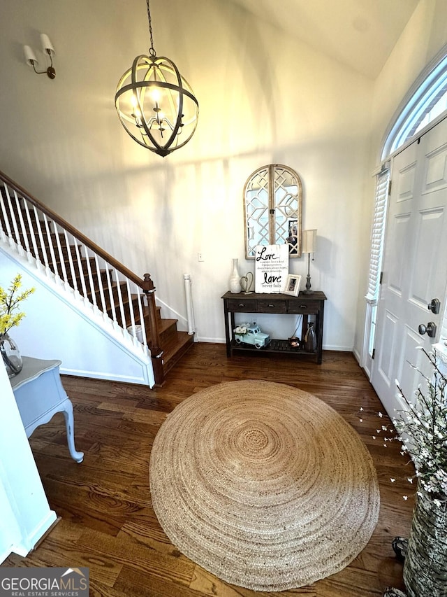 entryway featuring high vaulted ceiling, dark wood-type flooring, and an inviting chandelier