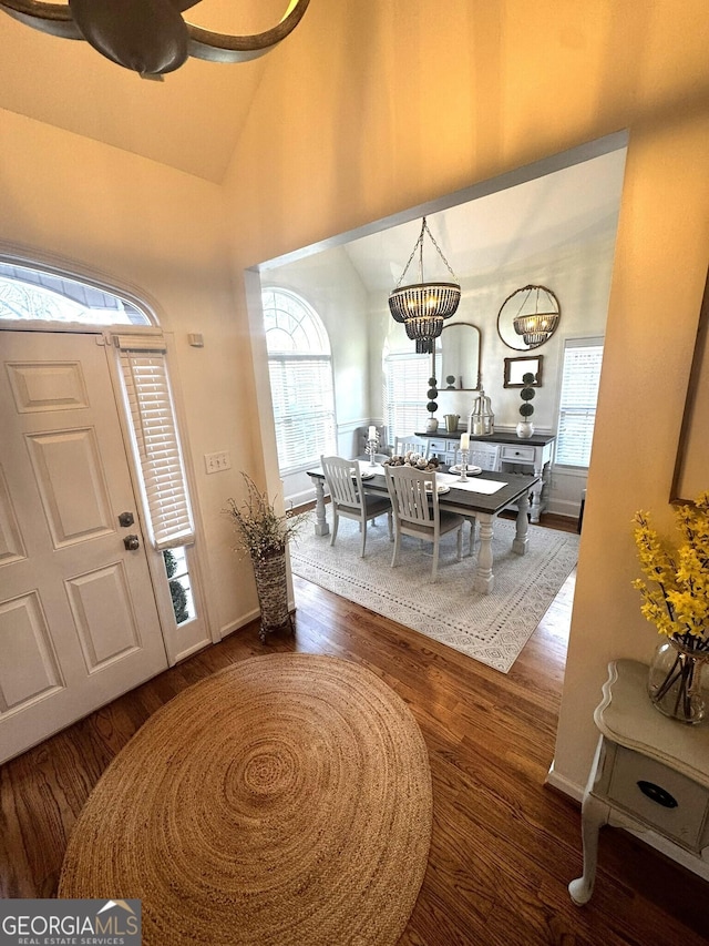 foyer entrance with dark hardwood / wood-style flooring, lofted ceiling, and a chandelier