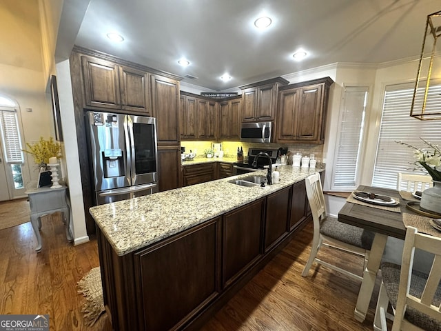 kitchen with stainless steel appliances, dark brown cabinets, sink, and decorative light fixtures