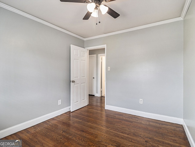 unfurnished room featuring crown molding, dark wood finished floors, and baseboards