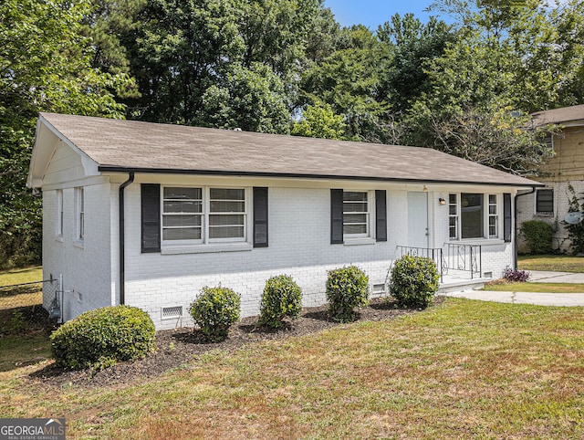 view of front facade featuring brick siding, fence, roof with shingles, crawl space, and a front lawn