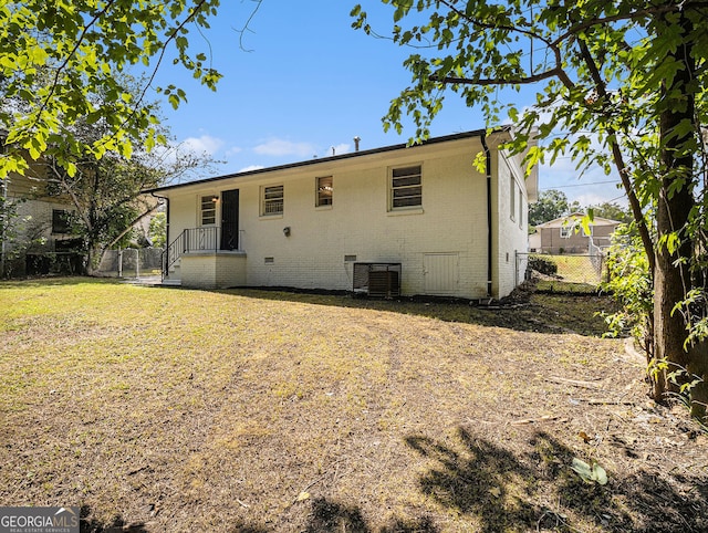 rear view of house with crawl space, fence, a yard, central air condition unit, and brick siding