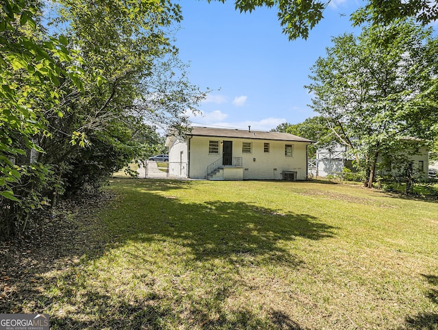 back of house with stucco siding, fence, cooling unit, and a yard