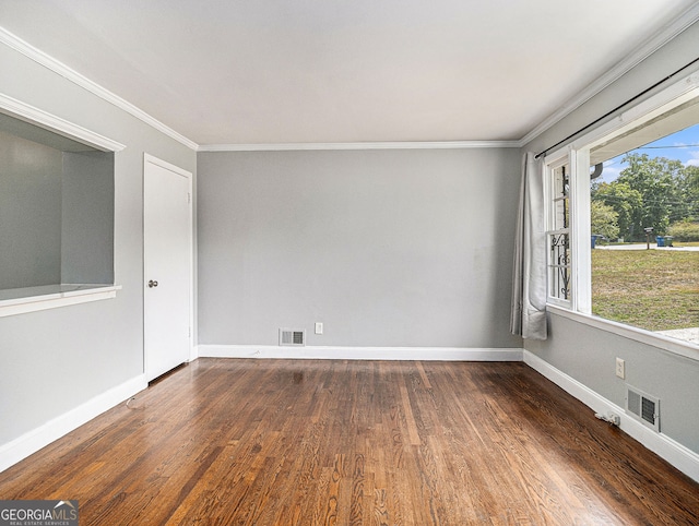 spare room with ornamental molding, wood finished floors, and visible vents