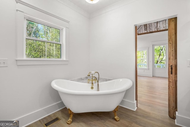 bathroom with ornamental molding, a bathtub, and hardwood / wood-style floors