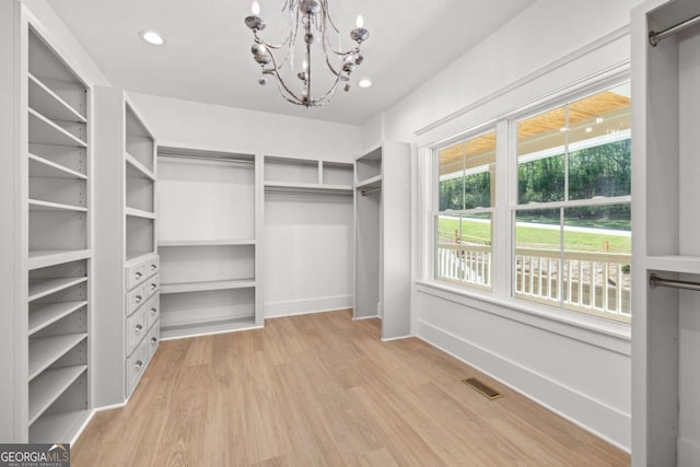 spacious closet featuring light hardwood / wood-style flooring and a notable chandelier