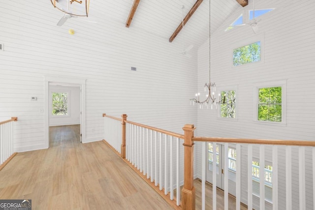 hall featuring beamed ceiling, high vaulted ceiling, a chandelier, and light wood-type flooring