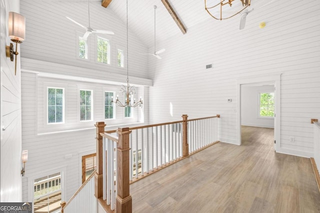 hall with beam ceiling, hardwood / wood-style floors, a notable chandelier, and high vaulted ceiling