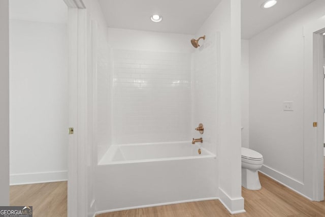 bathroom featuring hardwood / wood-style flooring, tiled shower / bath combo, and toilet