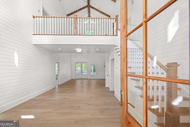 interior space with hardwood / wood-style flooring, high vaulted ceiling, and wood walls